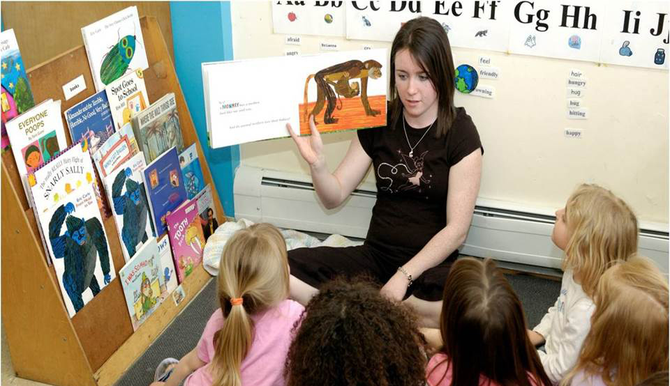 Teacher reading a book to pre-school children